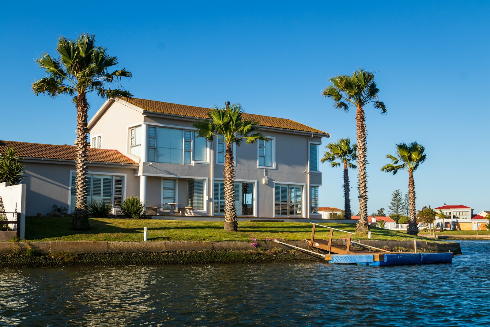 white and brown concrete house beside body of water during daytime, vacation home